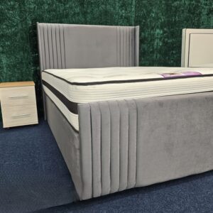 Close-up of grey velvet headboard with vertical stitching and plush padding