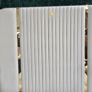 Close-up of cream velvet vertical panel headboard with gold trim